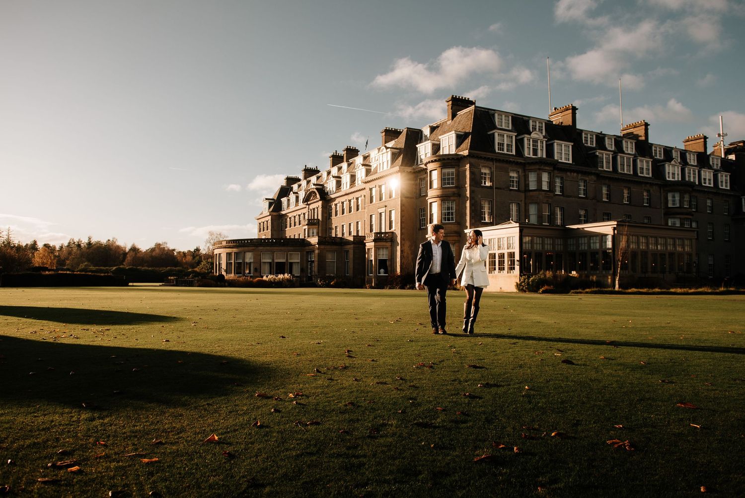 Historic building complex with manicured lawns and walking paths on a sunny autumn day.