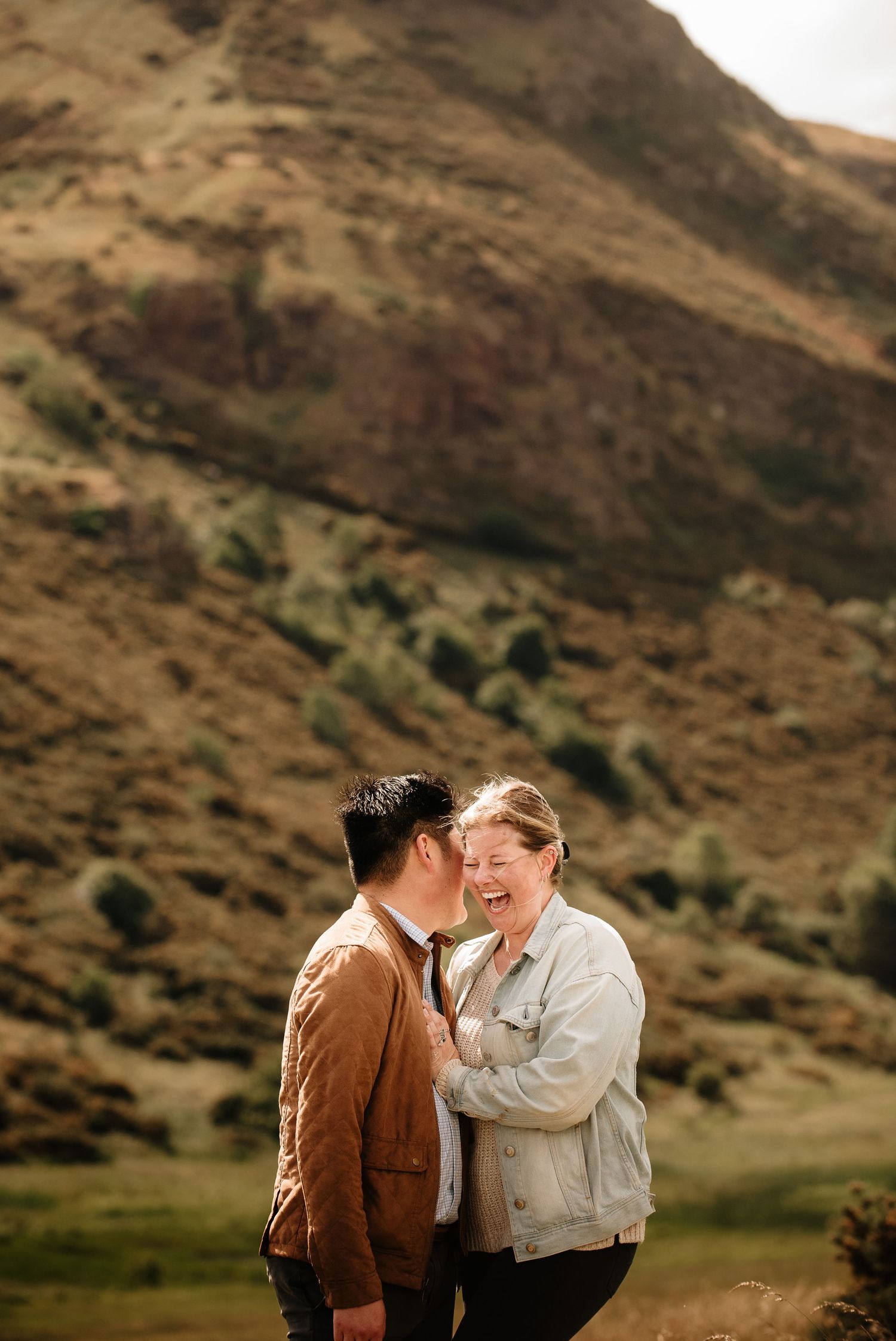 A couple shares an intimate moment against a backdrop of rugged mountain terrain.