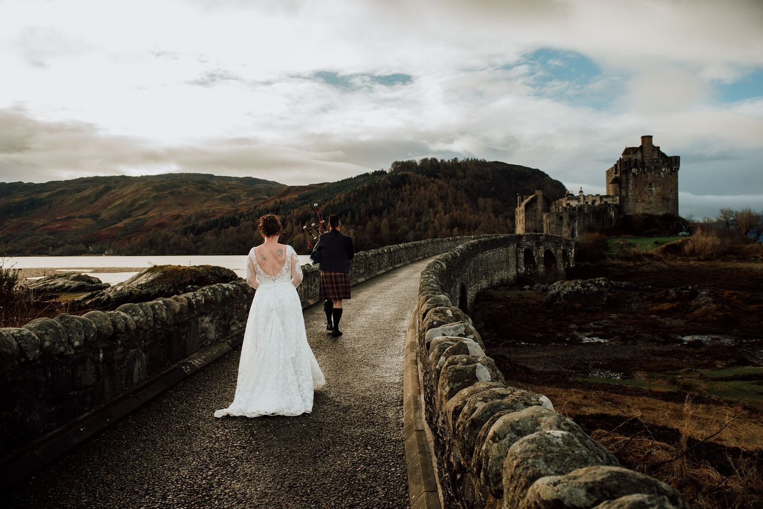 Couple walking along scenic coastal path with dramatic cloudy skies.