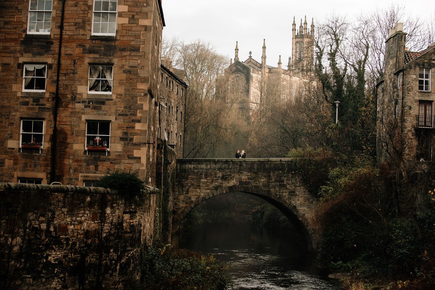 Stone buildings and church spires create a dramatic skyline along a historic Edinburgh street.