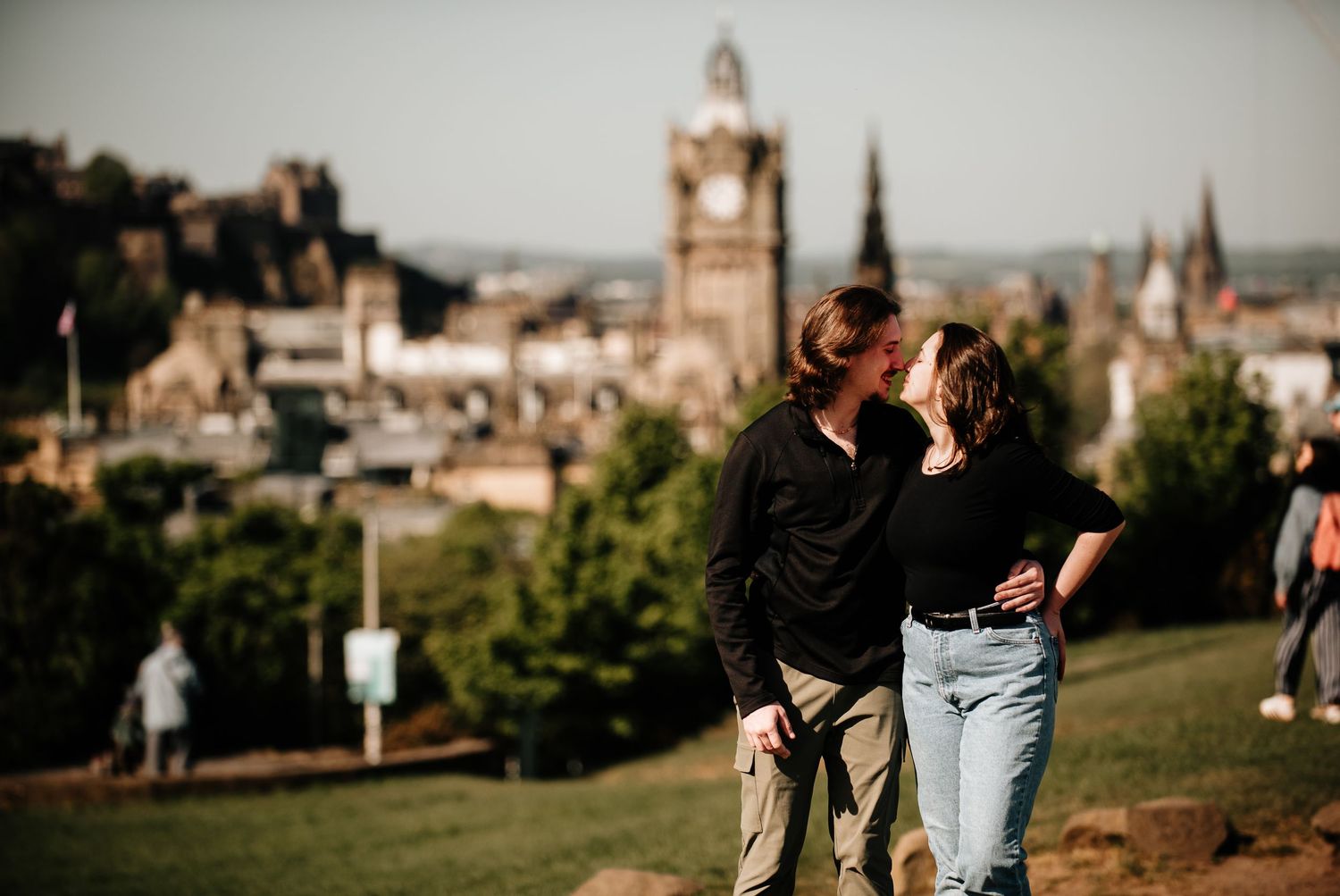 Romantic moment overlooking Edinburgh's historic cityscape with clock tower and architecture.