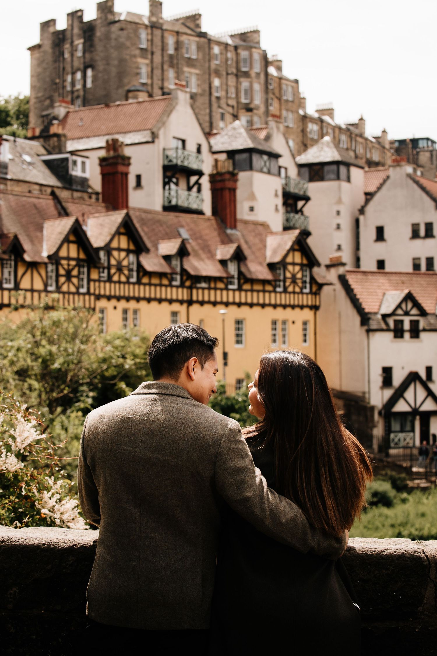 Couple sitting together admiring historic Edinburgh architecture with colorful Tudor-style buildings in the background.