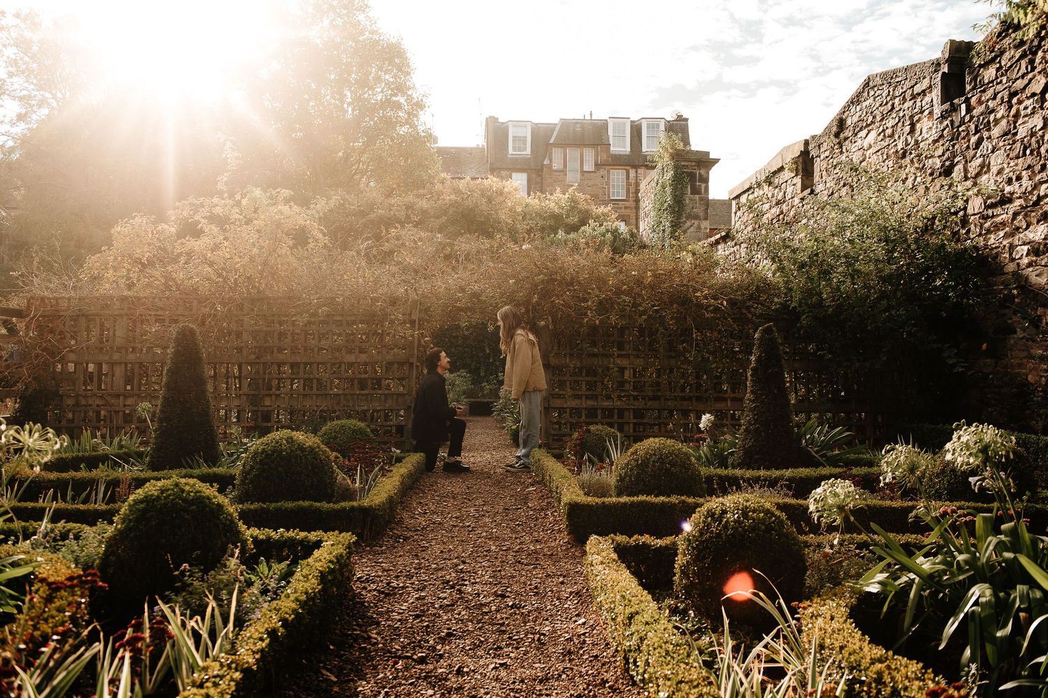 Formal garden path leading to historic castle ruins at sunset.