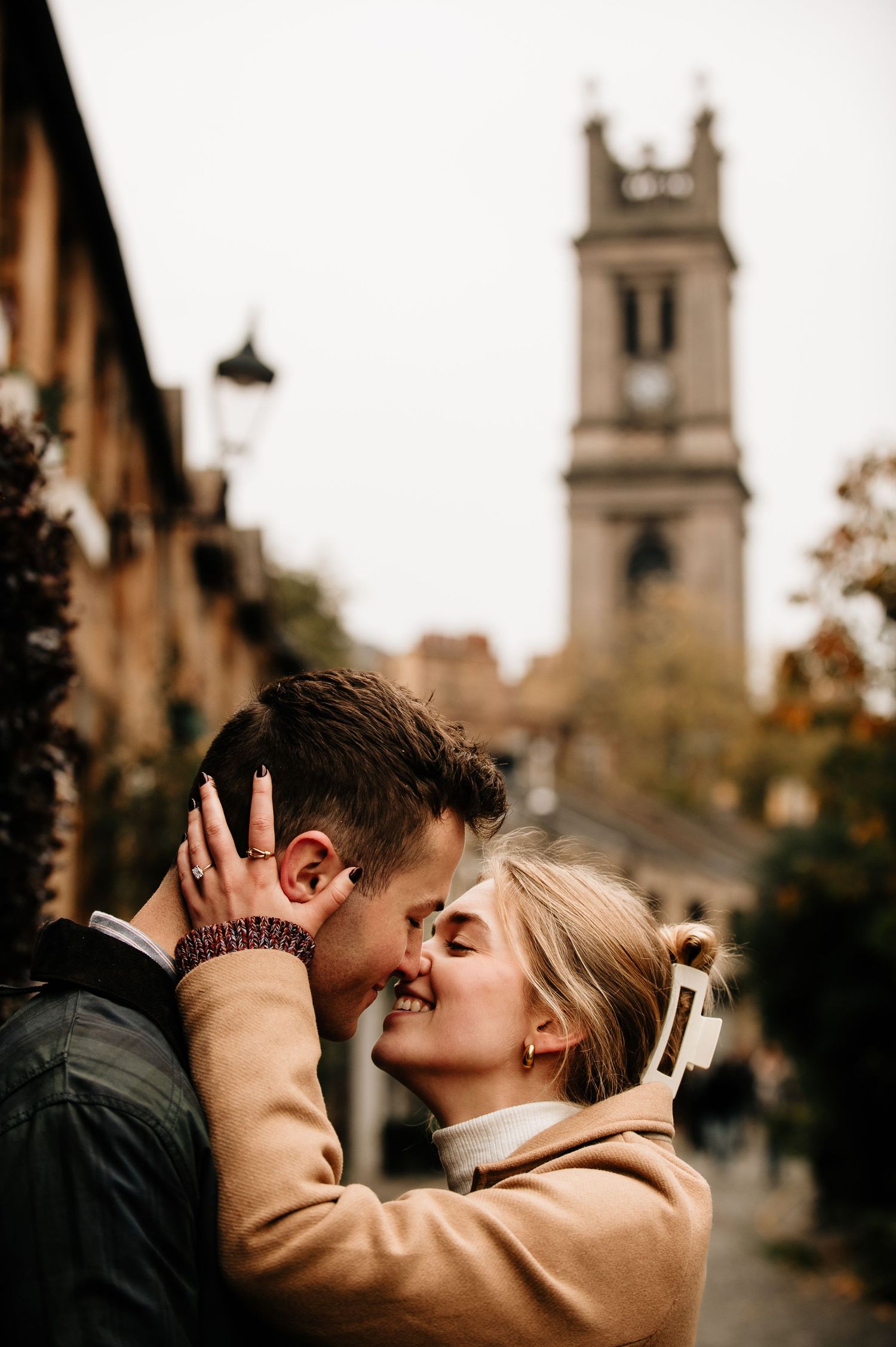 A romantic moment captured on a quaint cobblestone street with historic architecture in the background.