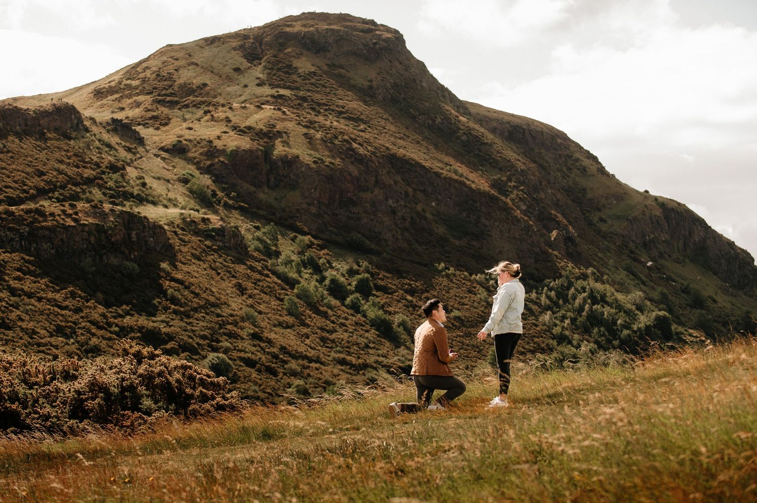 A couple sharing a special moment on a mountainside with dramatic landscape views.
