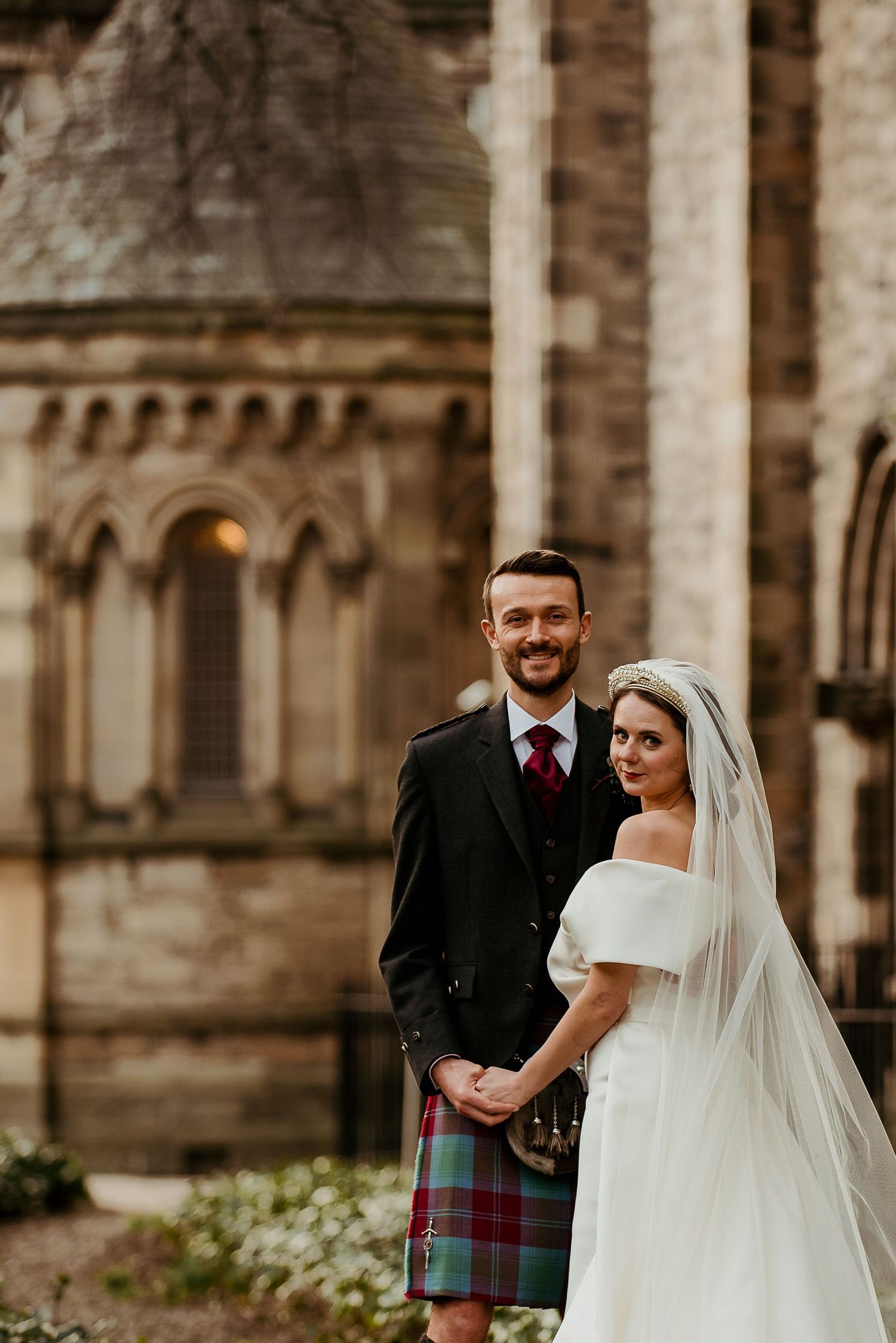 Wedding ceremony outside historic stone church with Scottish tartan details.