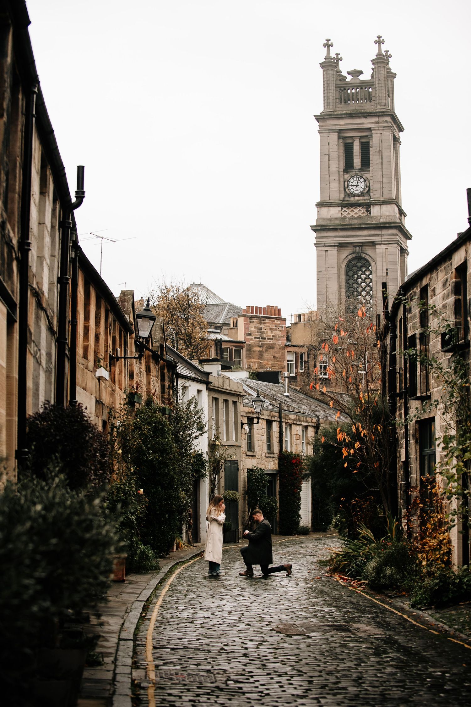 Historic cobblestone streets and church towers create a moody Scottish townscape.