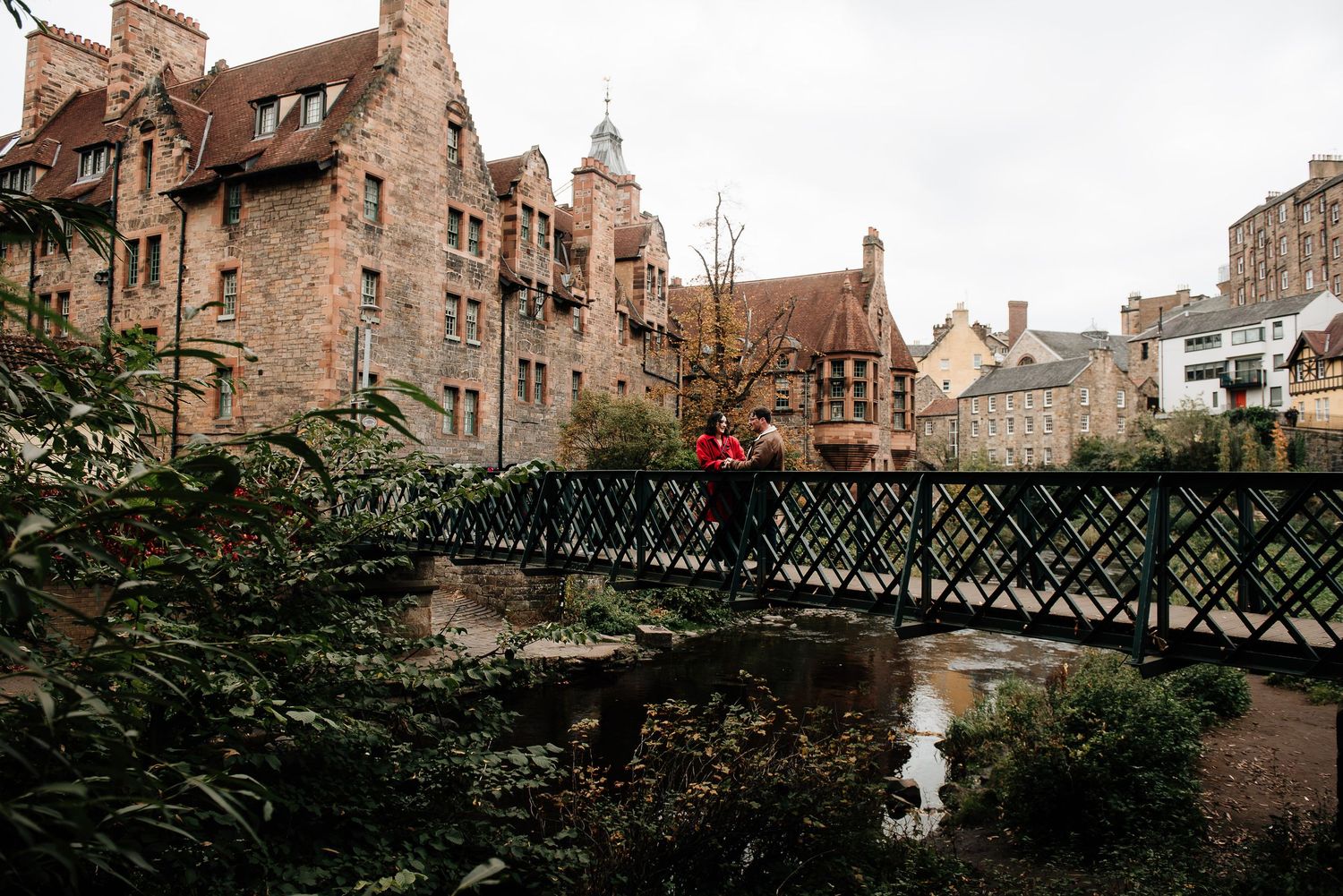Historic stone buildings and iron footbridge over a stream in Edinburgh's Dean Village.