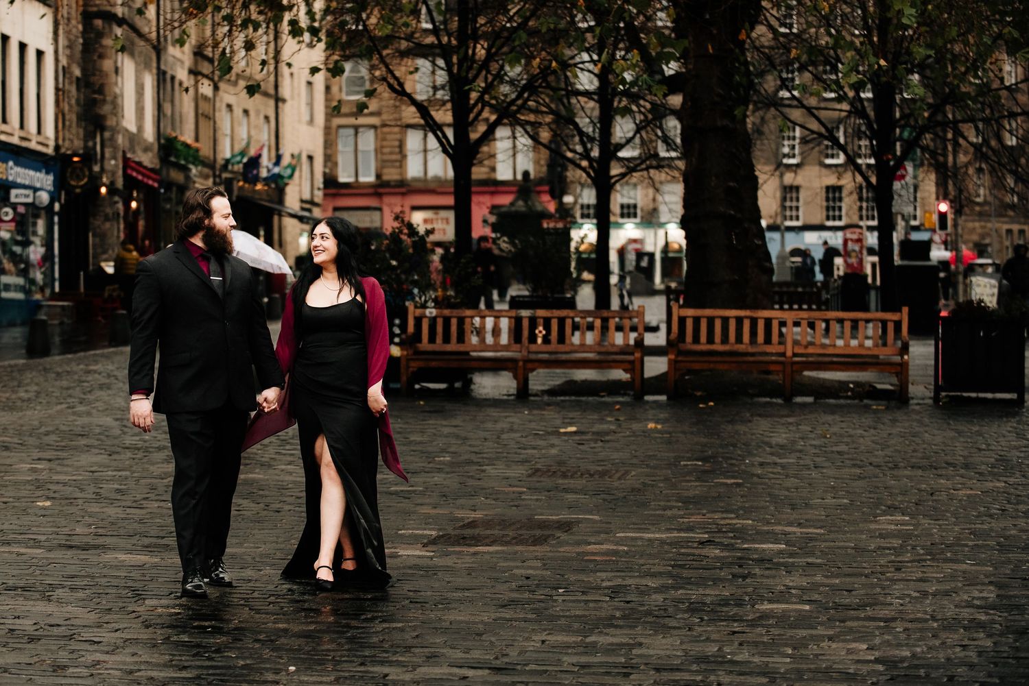 A couple dances together on a cobblestone plaza in an elegant, romantic setting at dusk.