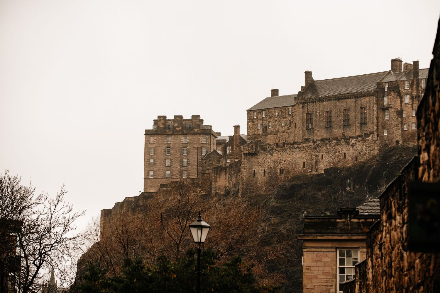 Dramatic view of Edinburgh Castle perched atop volcanic rock at dusk.