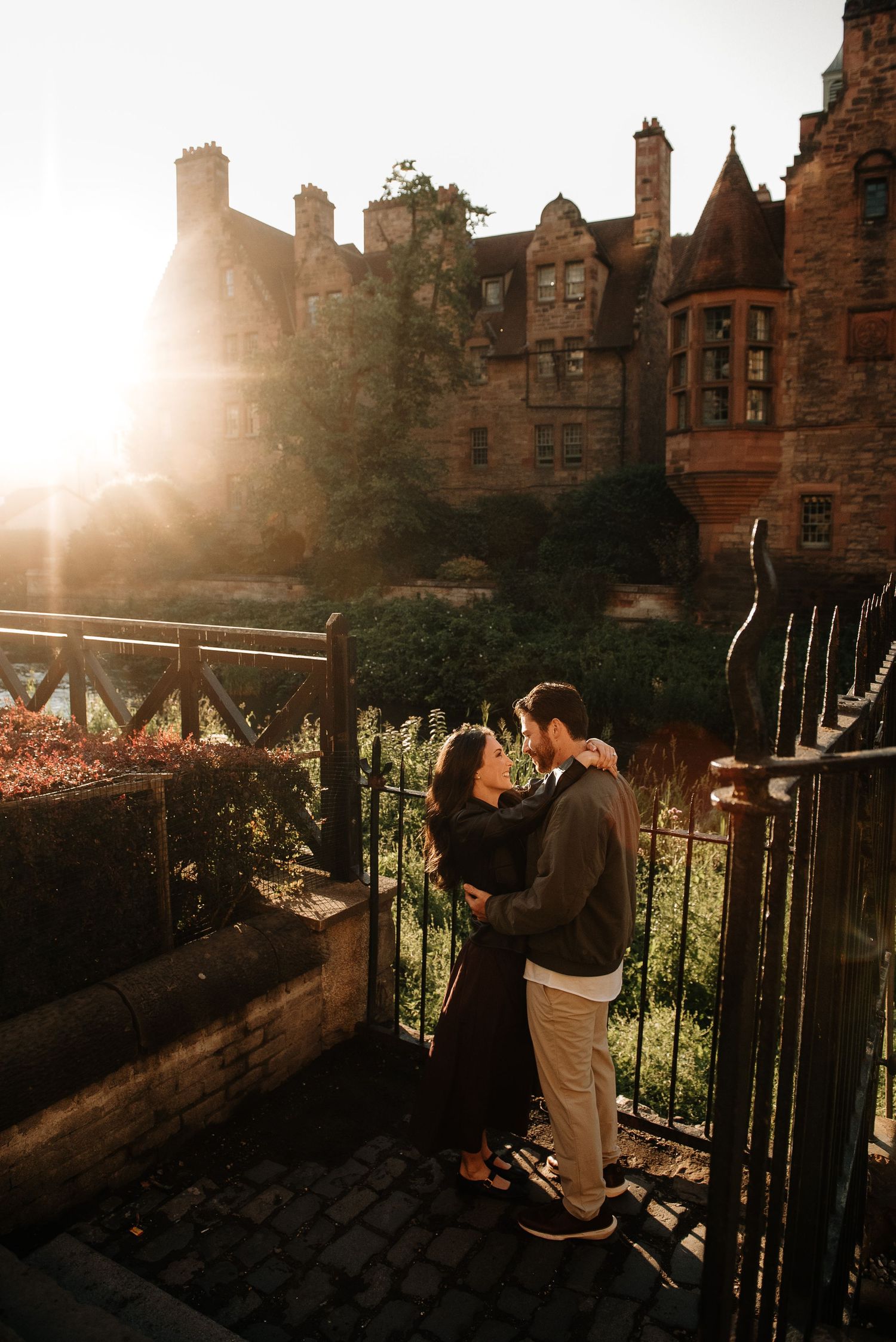 Golden hour engagement photos with sunlit stone buildings creating a romantic atmosphere.