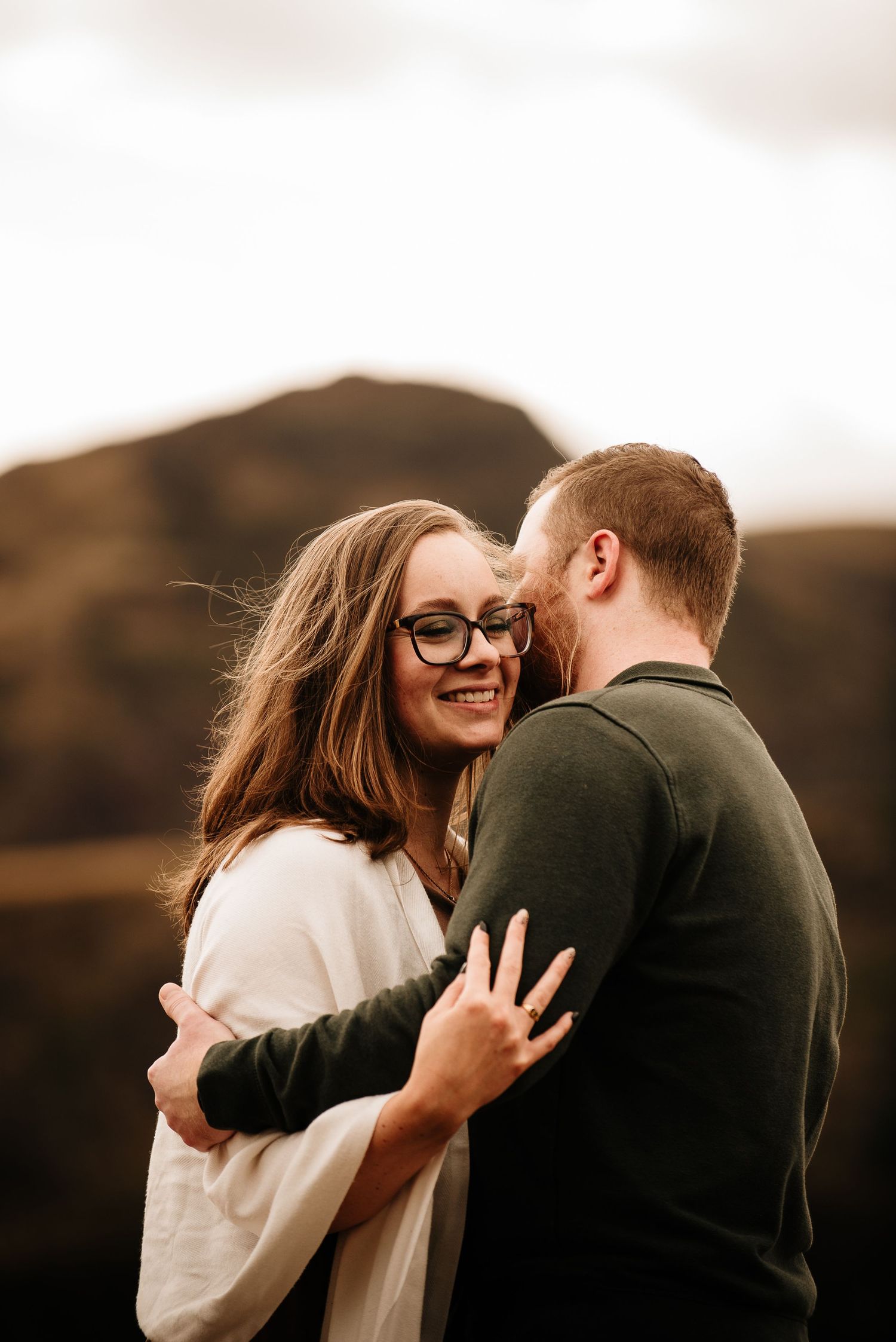 Candid moment of laughter and embrace against a mountain landscape at golden hour.