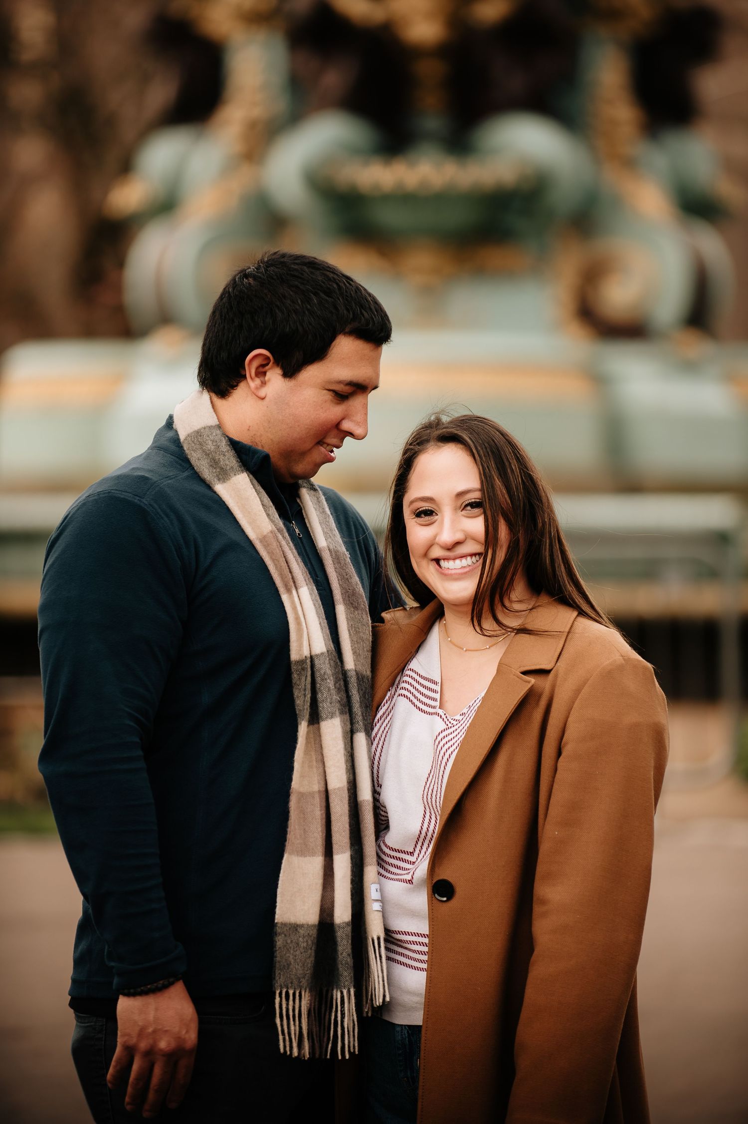A couple shares intimate moments outdoors in autumn wearing cozy coats and scarves during a romantic photoshoot.