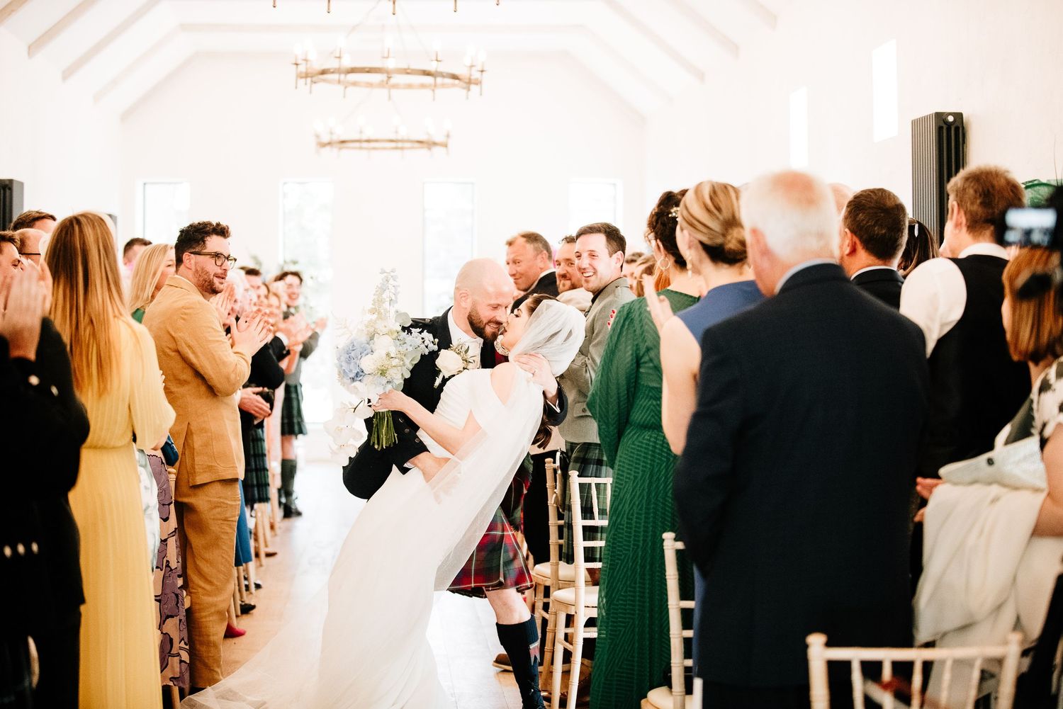 Wedding reception in a bright white room with guests celebrating.