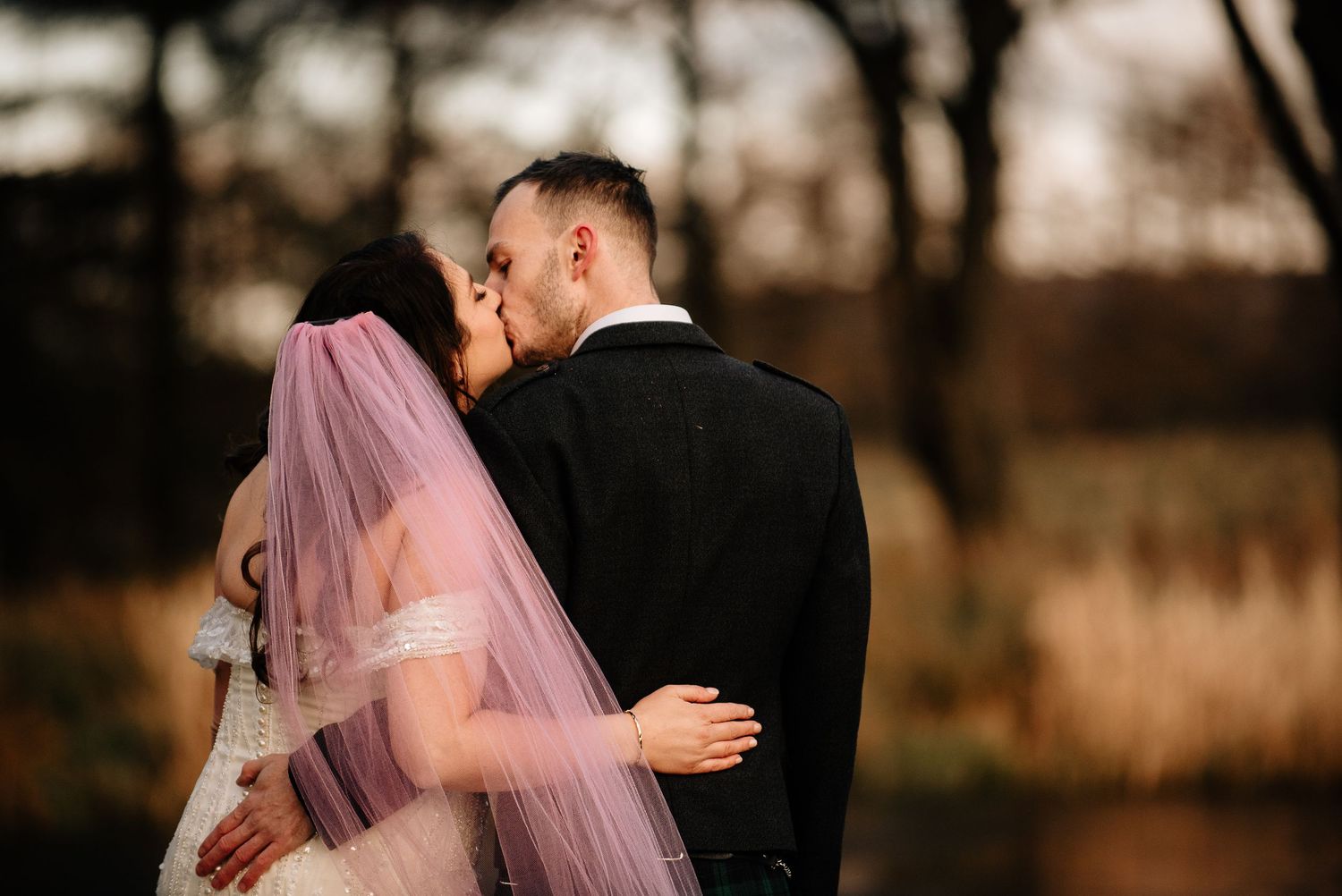 Newlyweds share intimate moment in autumn woodland setting.