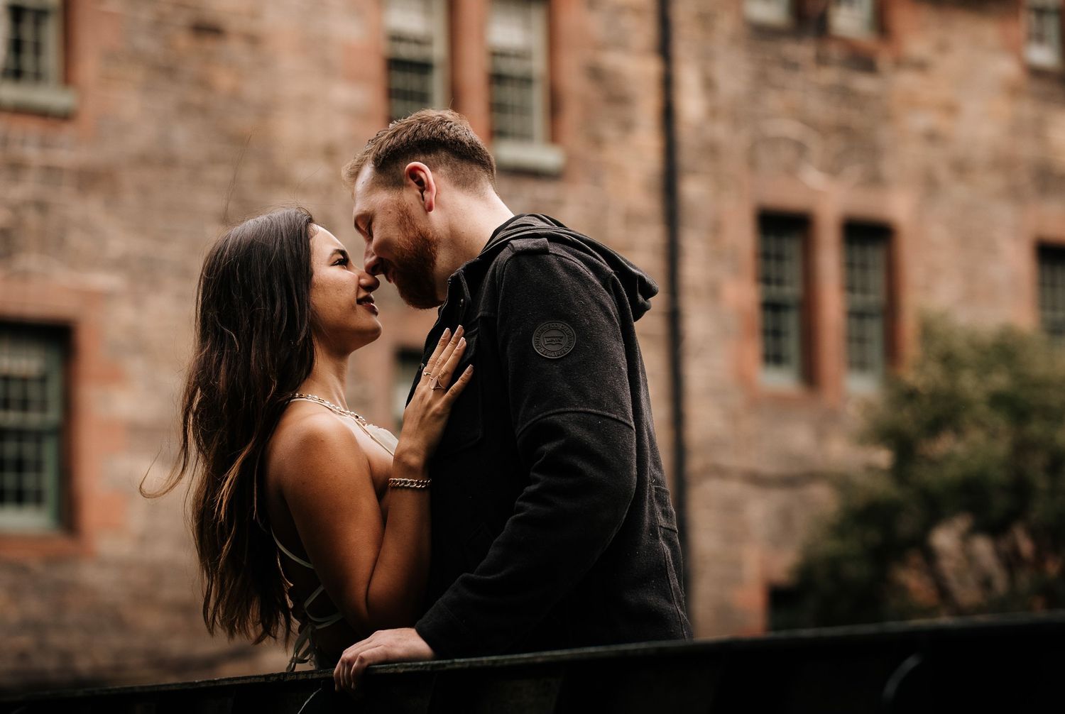 Intimate couple portrait against weathered stone walls of historic Scottish architecture.