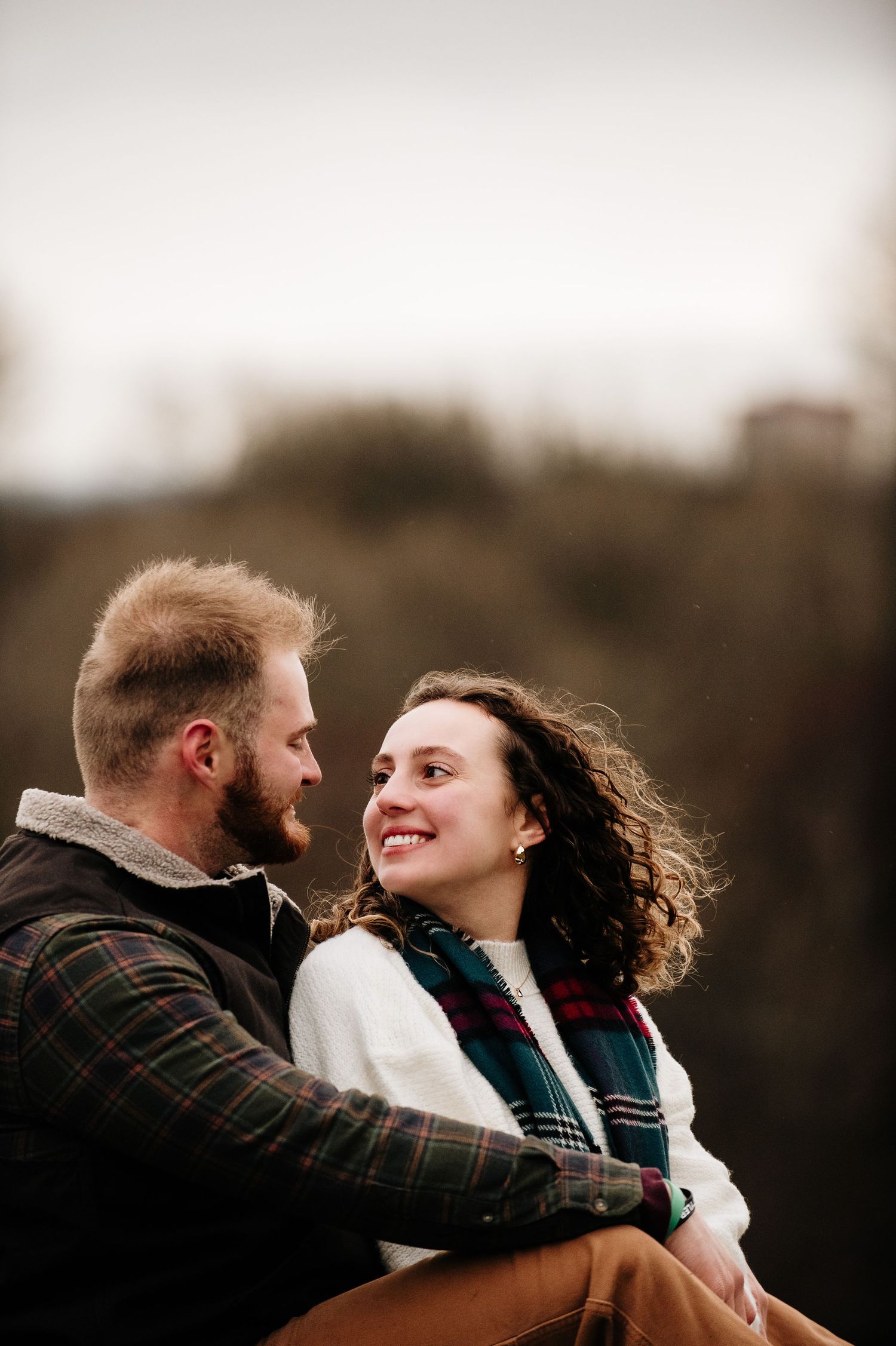 Couple embraces during sunset photoshoot in moody winter setting.