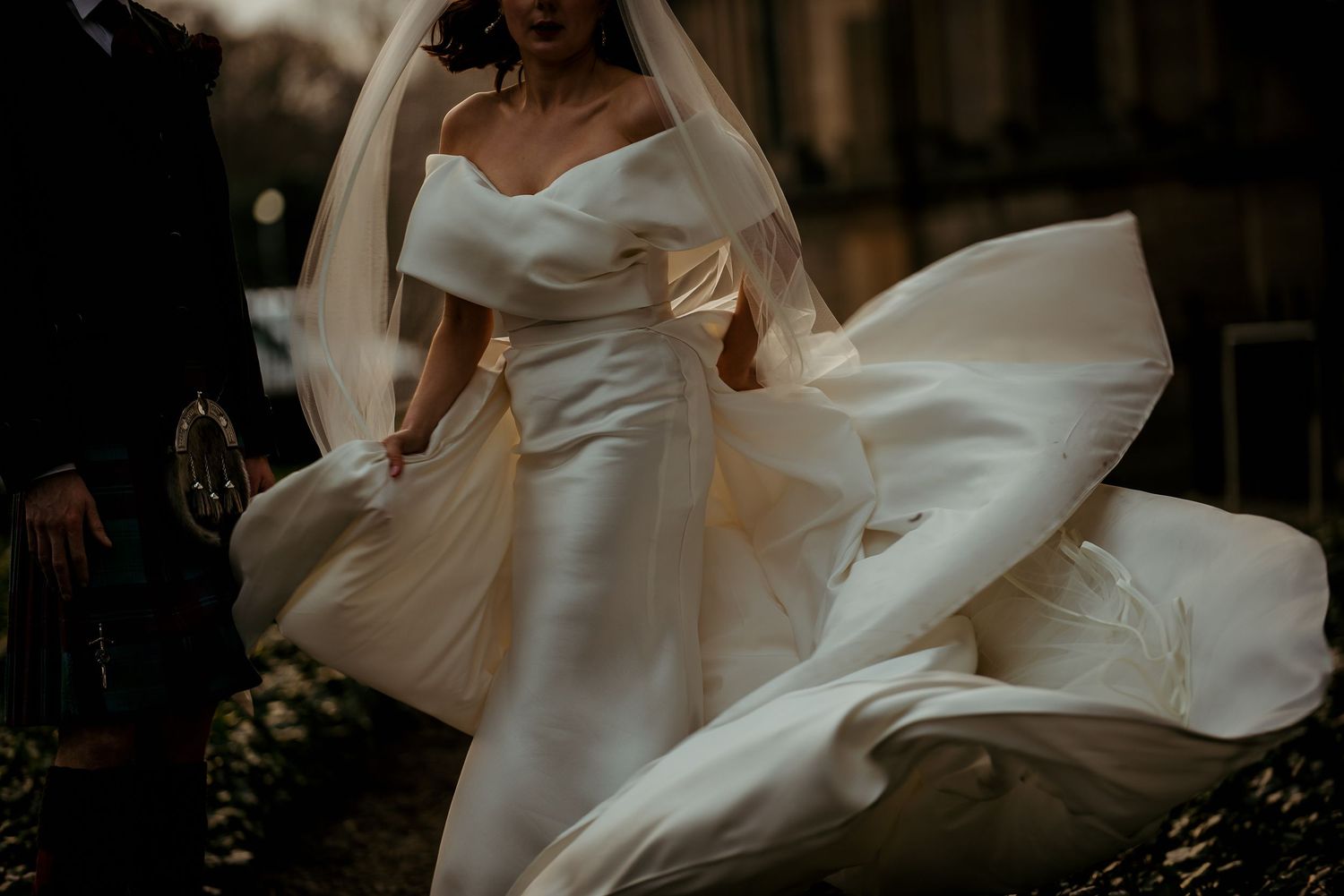 White wedding gown flowing in gentle motion against dark background.