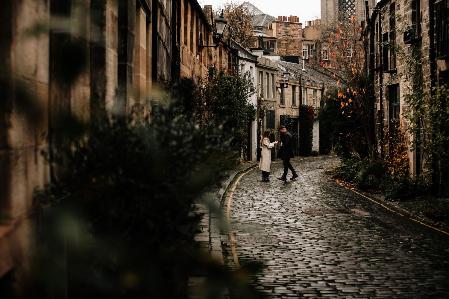 Atmospheric view down a winding cobblestone street lined with historic Scottish architecture.