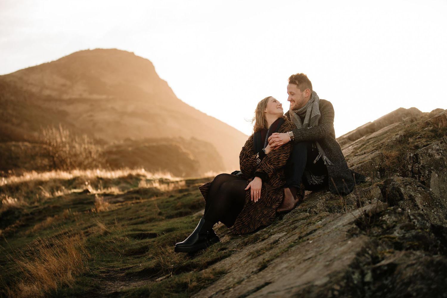 Romantic sunset photoshoot on rocky mountain terrain with warm lighting.