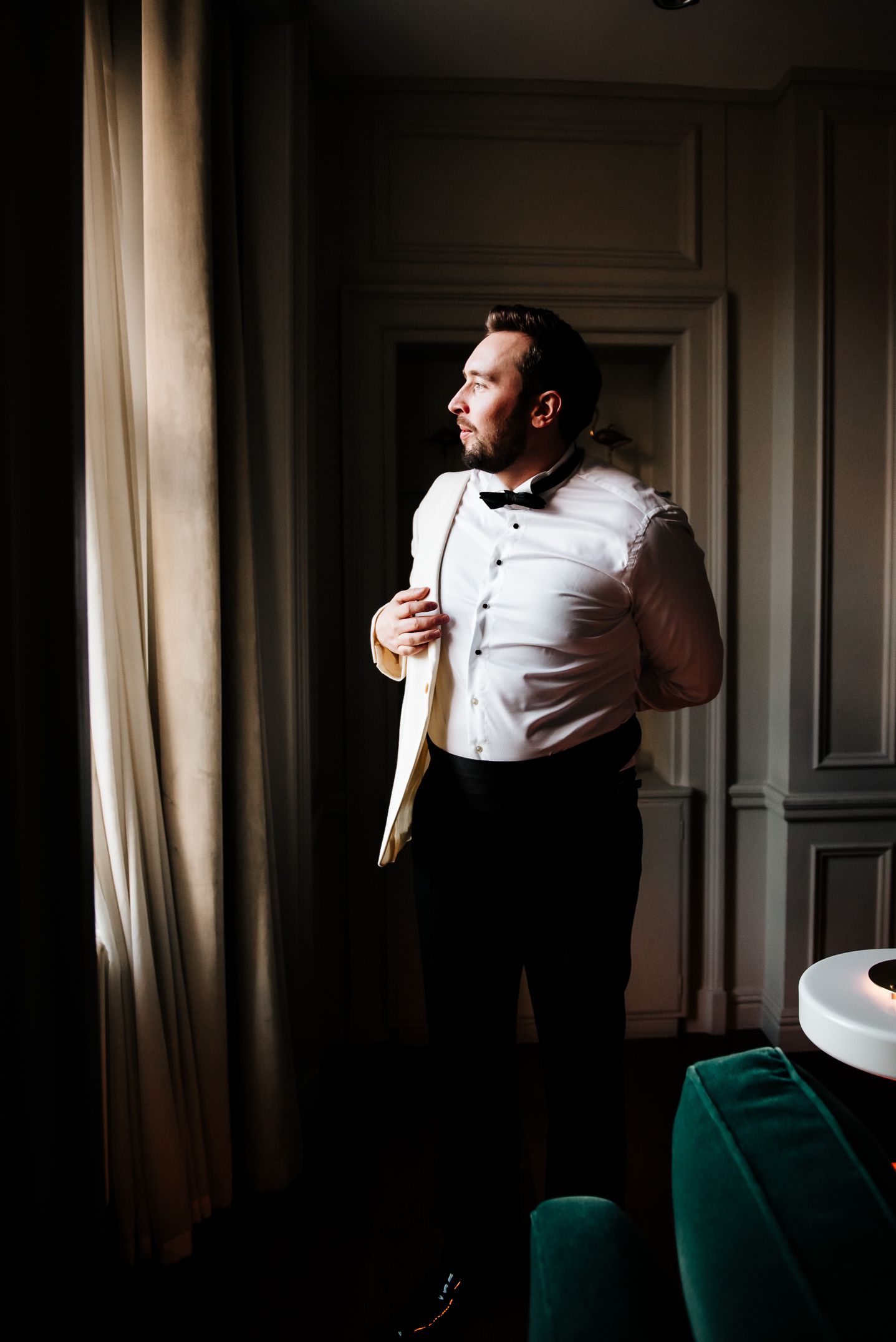 Dramatic light falls on formal attire during wedding preparation in elegant room.