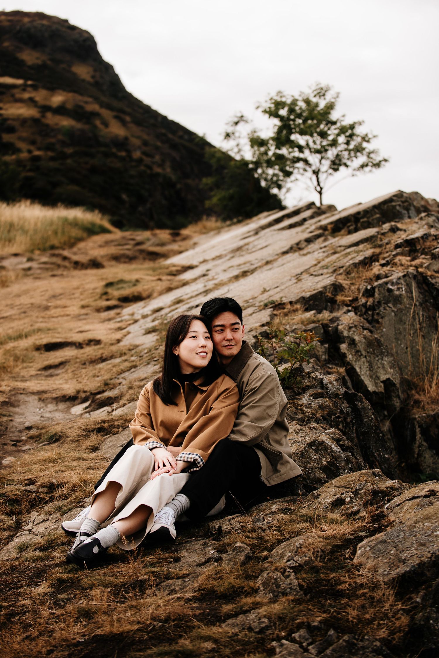 Couple resting on rocky outcrop with mountain views.