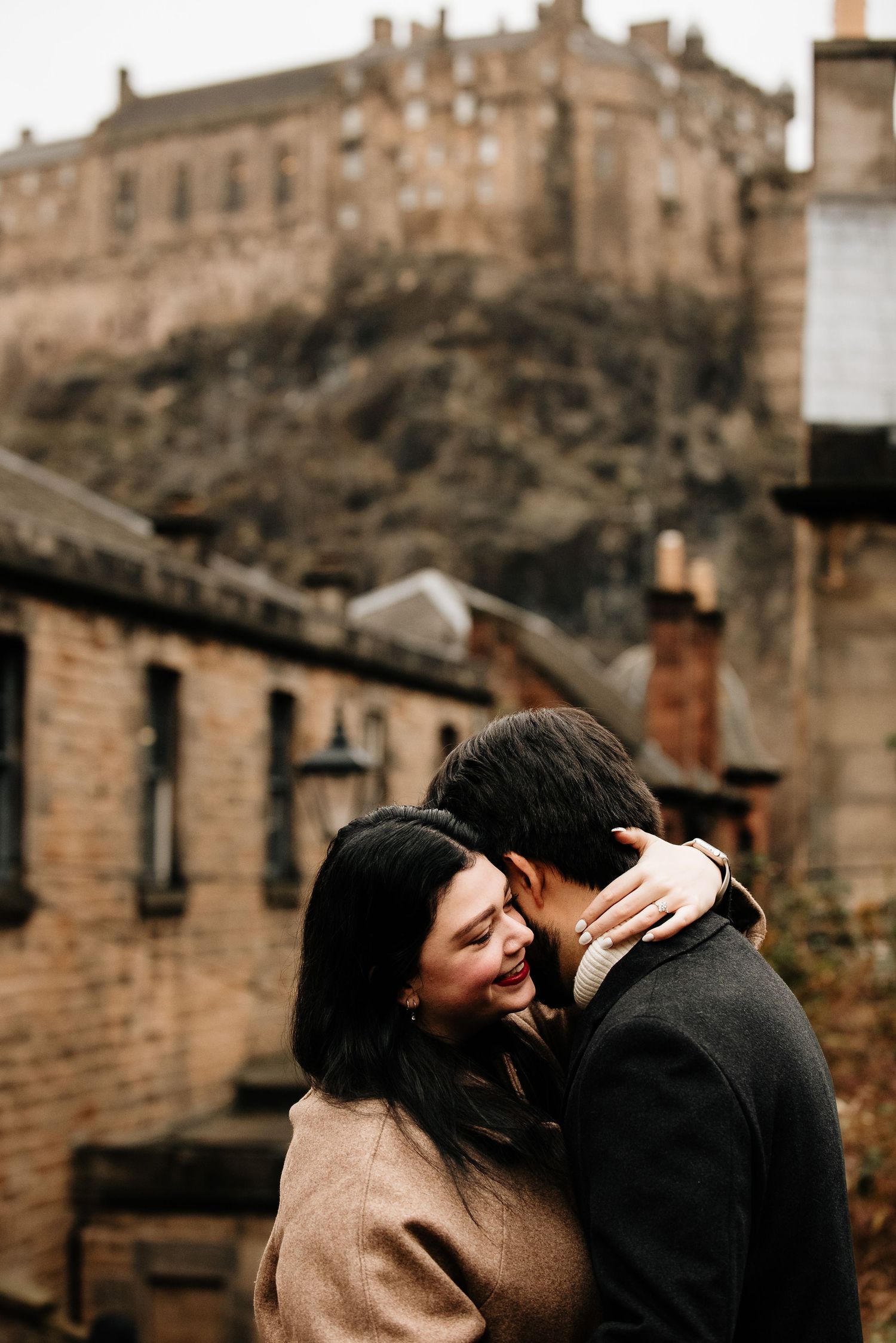 Romantic embrace beneath Edinburgh Castle on a moody winter day.