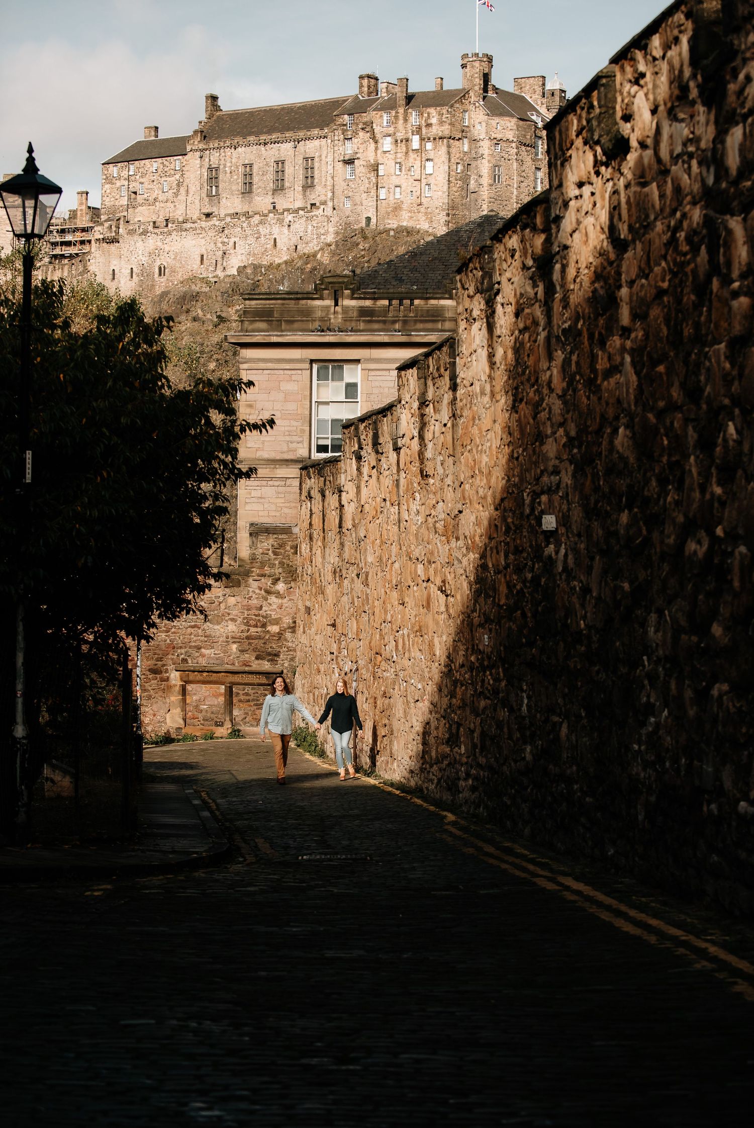 Stone-walled pathway leading towards Edinburgh Castle on an autumn evening.