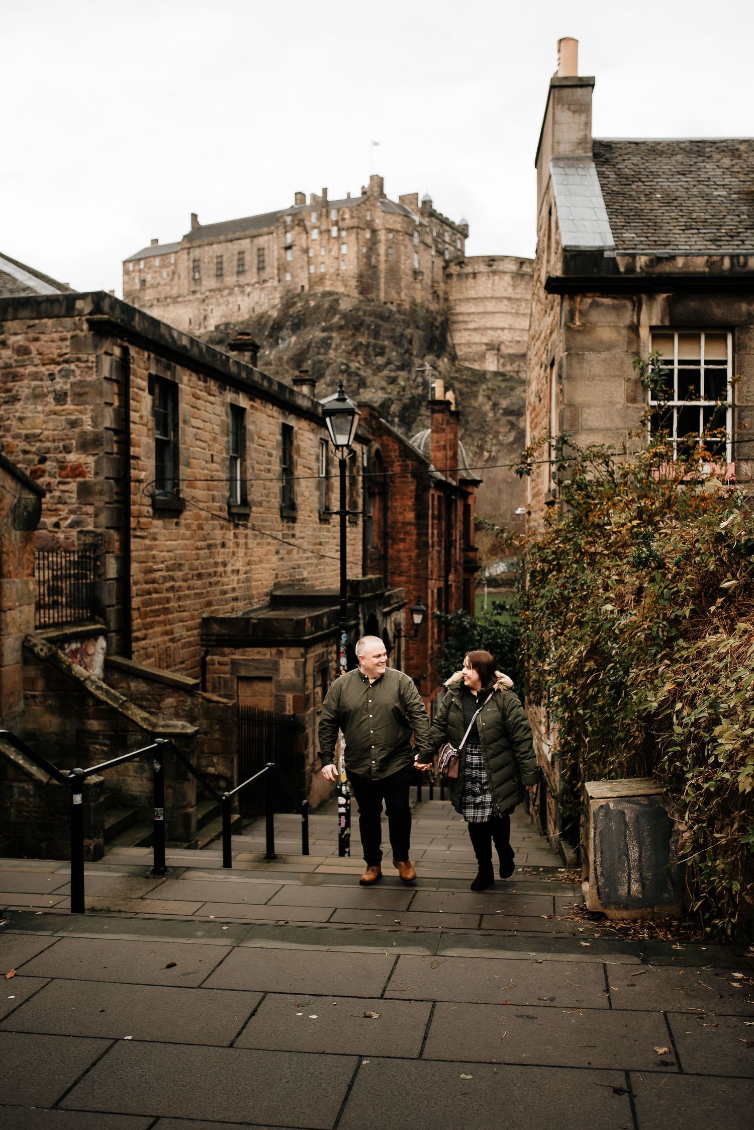 Stone-paved walkway with traditional architecture and Edinburgh Castle looming in the distance.