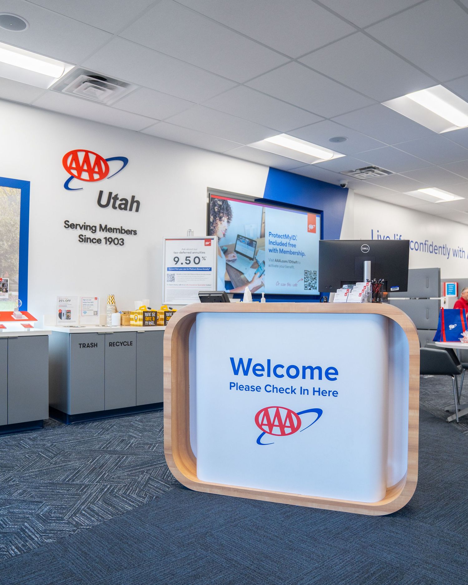 AAA Utah branch office welcome desk with check-in sign, serving members since 1903, featuring blue carpet and branded decor.