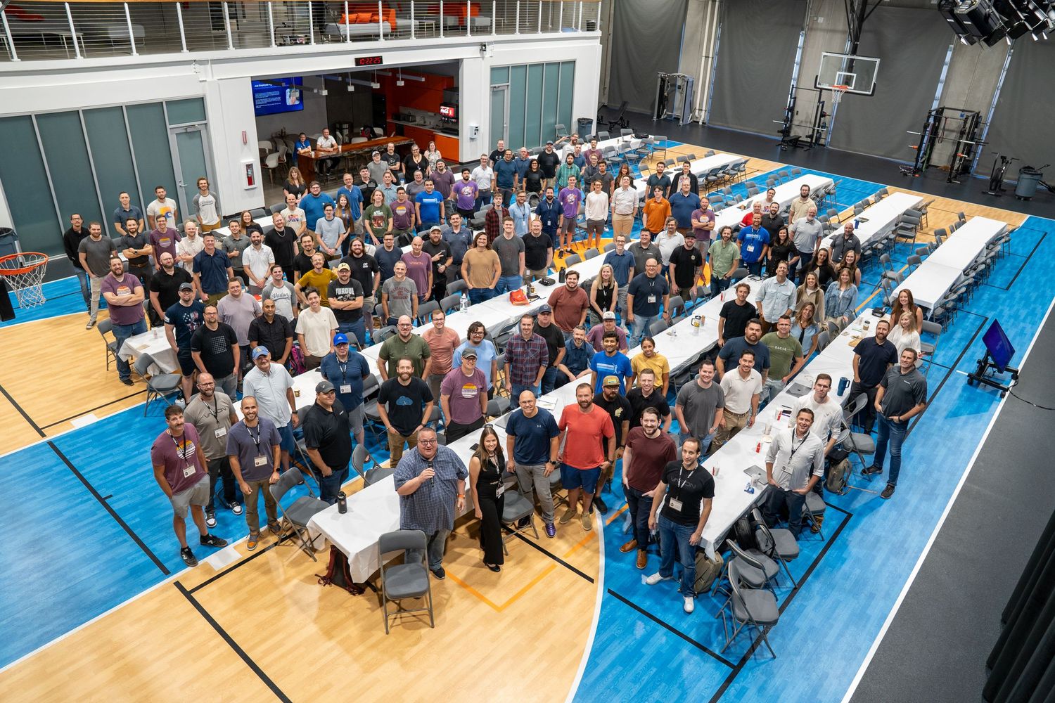 Large group of professionals gathered on an indoor basketball court for a corporate event or team meeting.
