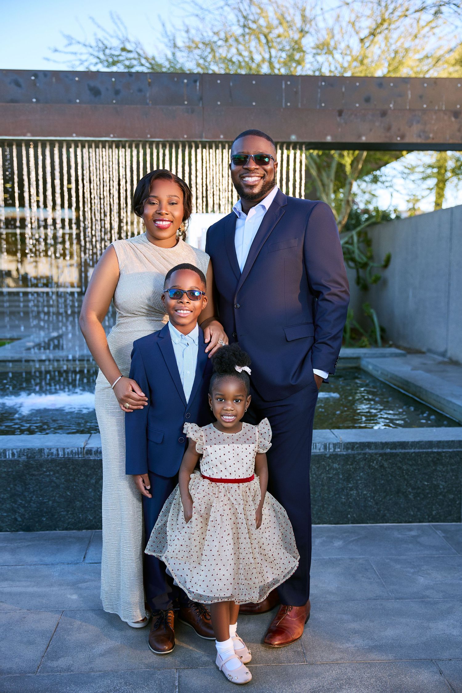 Family poses together near modern water feature in outdoor setting.