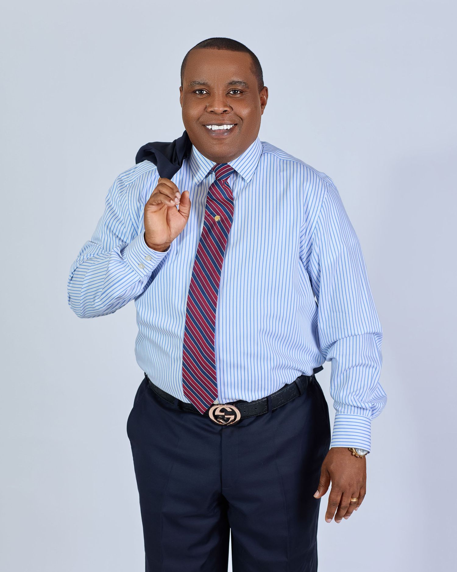Professional business portrait in striped shirt and tie with navy slacks.