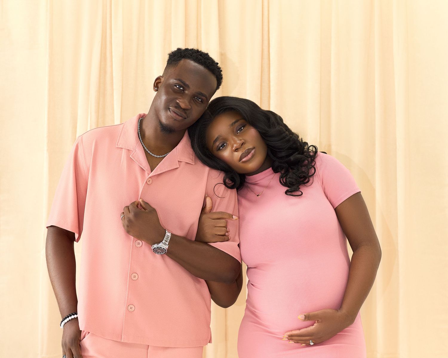 A couple in matching pink outfits shares tender moments in a photo series.