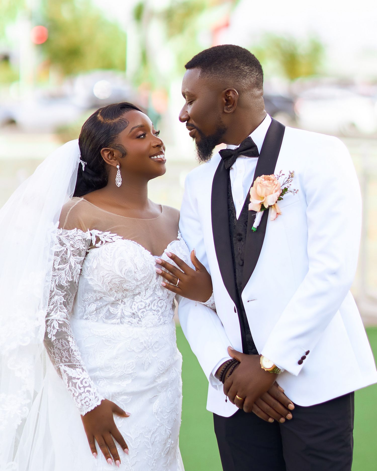 Couple shares tender moment in white wedding attire outdoors.