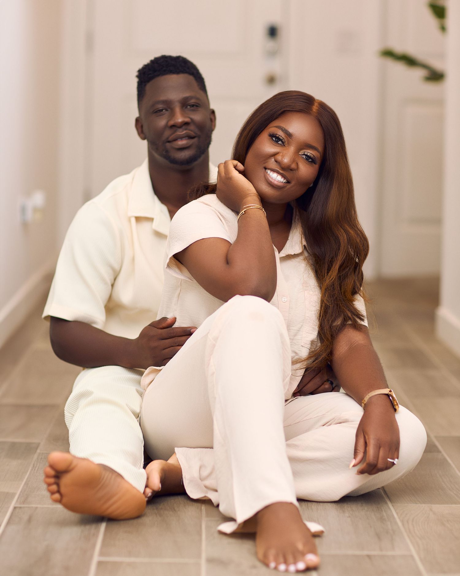 Couple in matching white outfits poses for intimate photoshoot on floor.