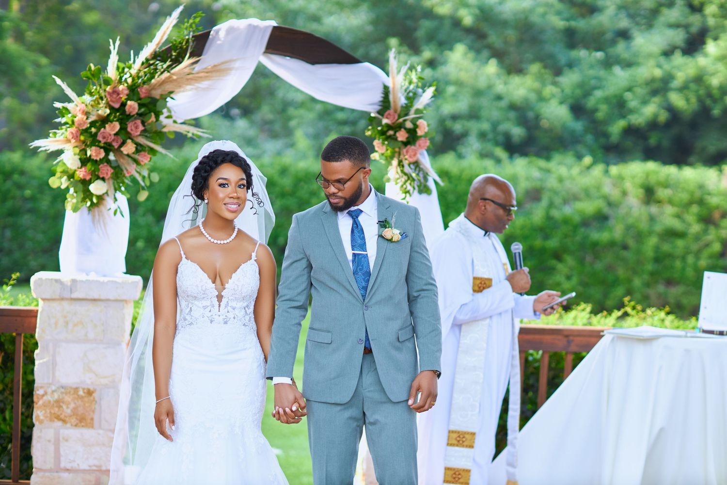 Wedding party members walk together in an outdoor garden setting.