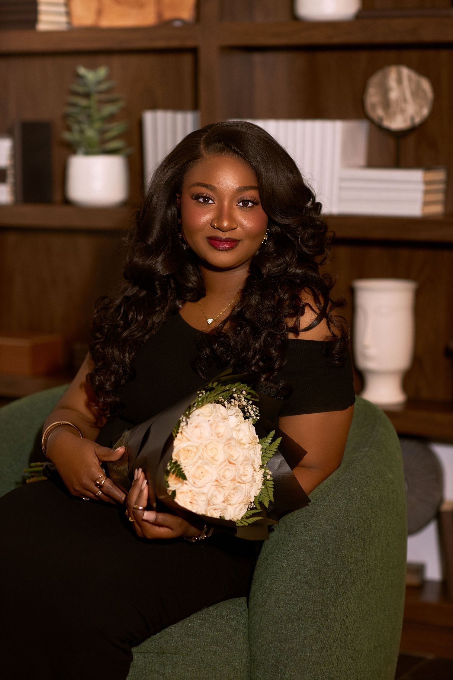 Elegant portrait series in dark green dress holding white floral bouquet in warm-toned interior.
