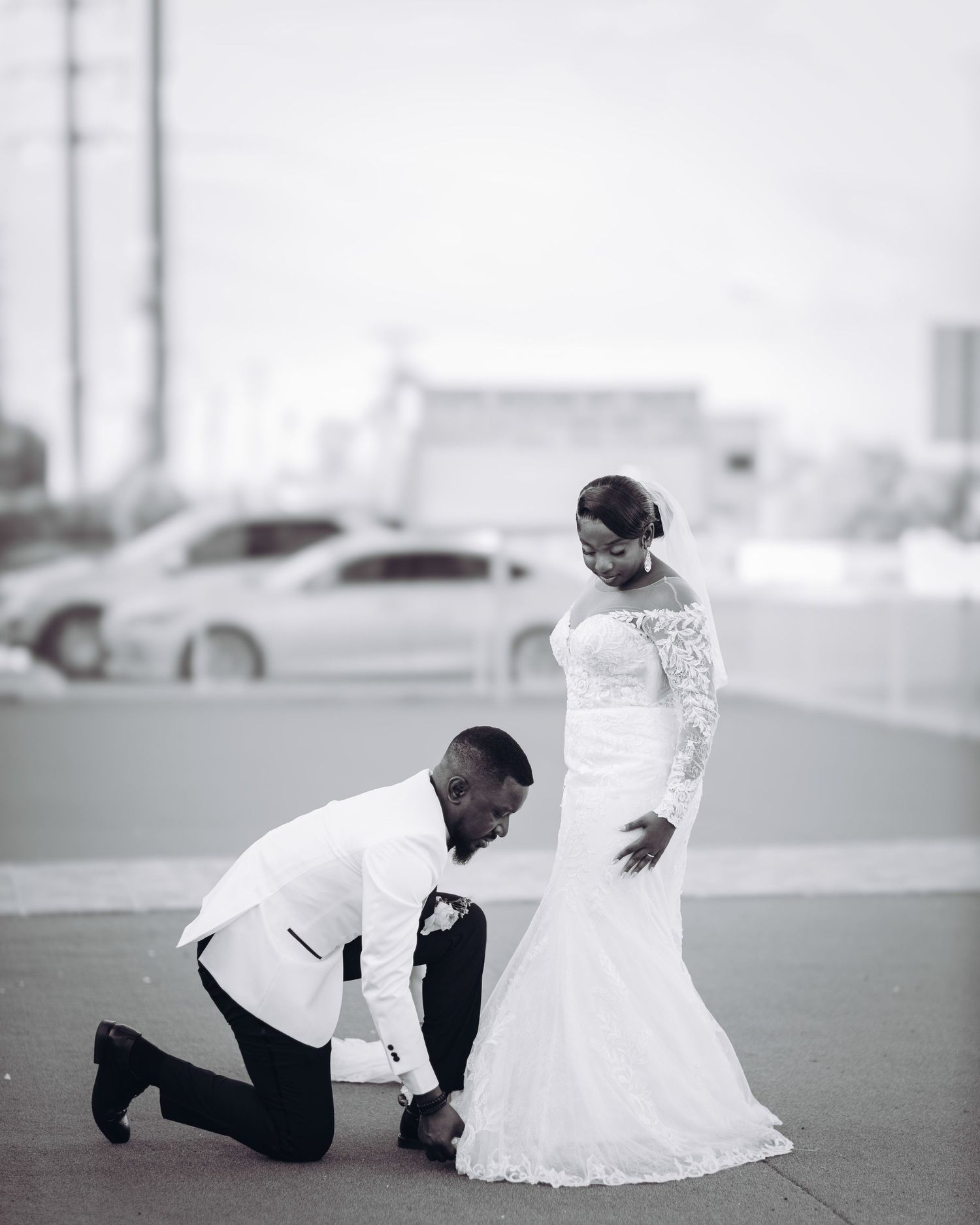 A couple in wedding attire creates dramatic poses during an outdoor photoshoot.