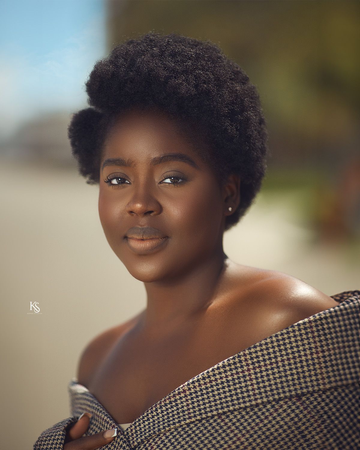 Professional headshots in black and white checkered top with natural hair styling.