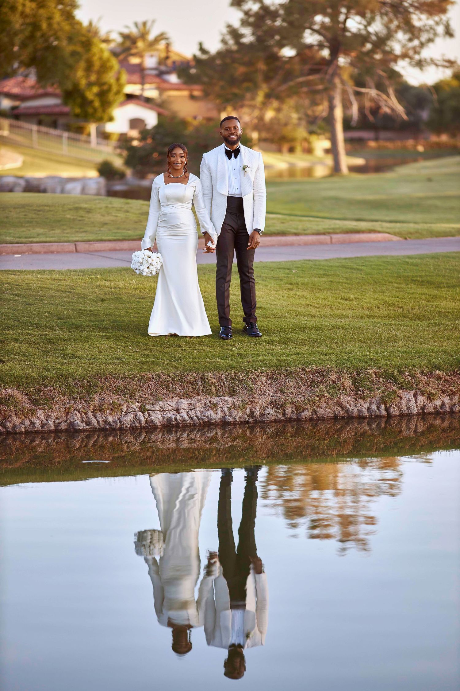 Couple's reflection appears in lake water during sunset wedding photoshoot.