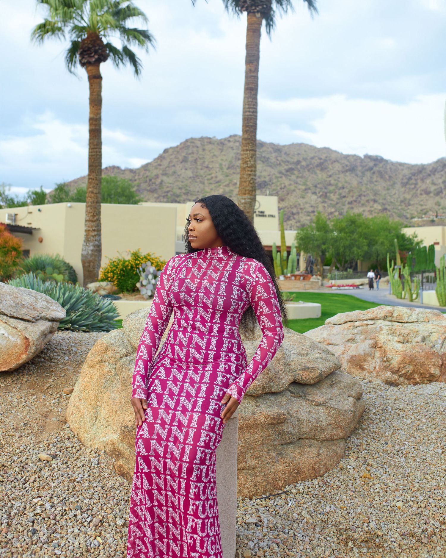 Fashion shoot featuring flowing pink patterned dress in desert setting with palm trees.