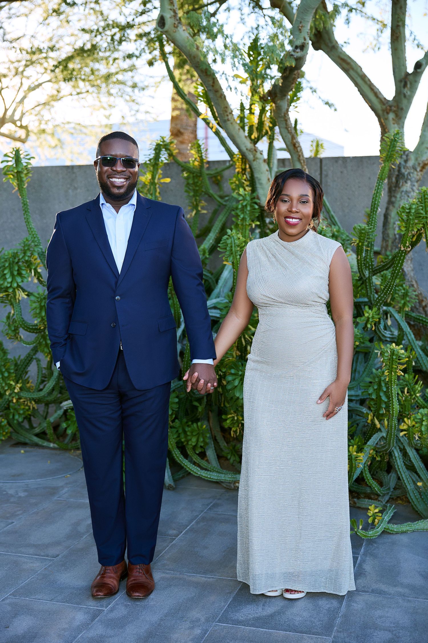 Couple poses for casual outdoor portraits against garden backdrop with natural lighting.