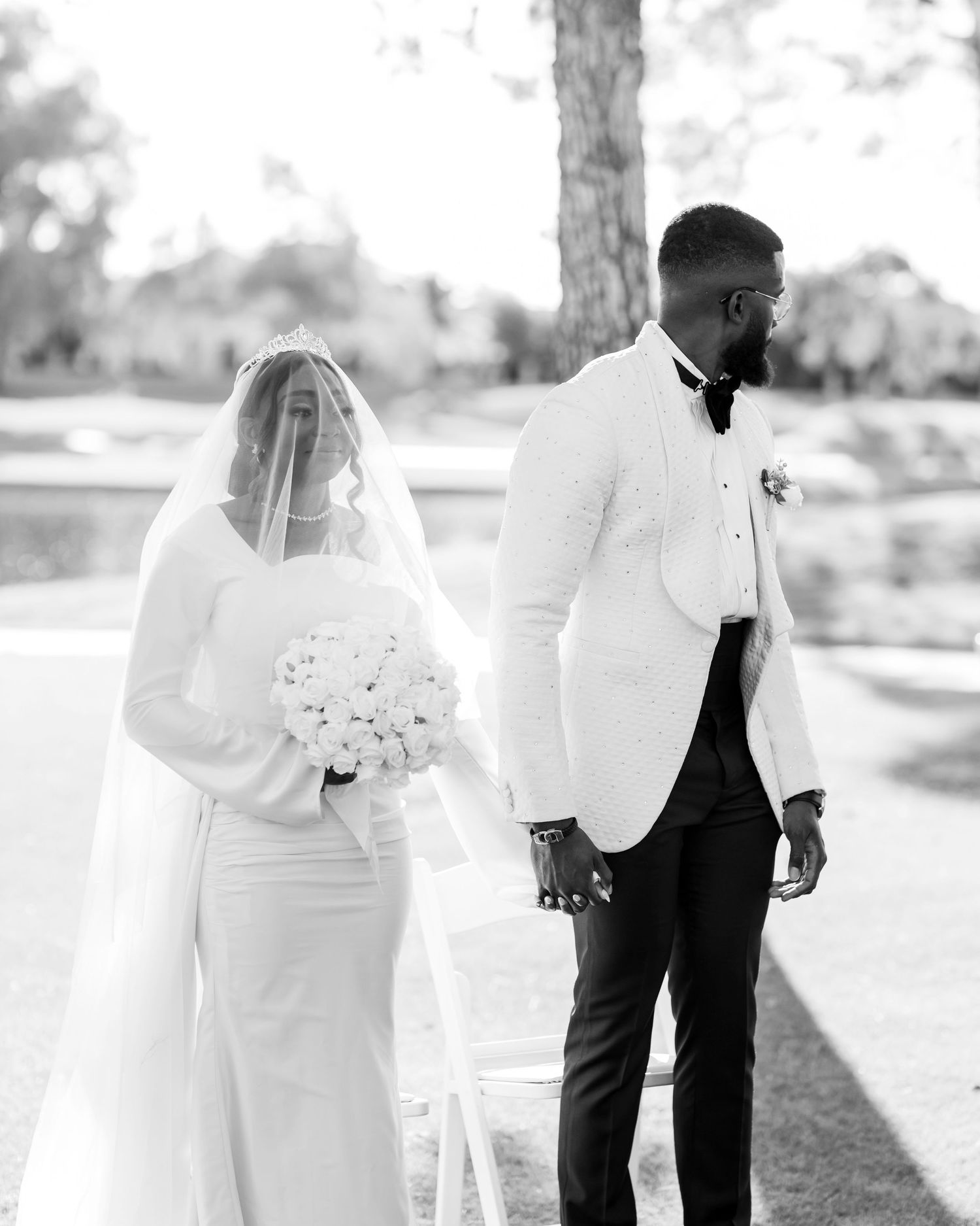 A black and white wedding photo series showing romantic moments between a couple in formal attire outdoors.