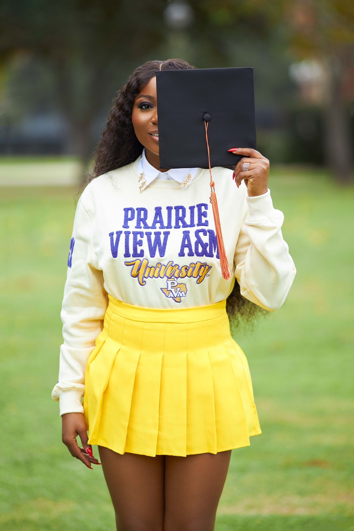 Yellow pleated cheerleader skirt with Prairie View A&M University logo and cream colored top shown in outdoor setting.