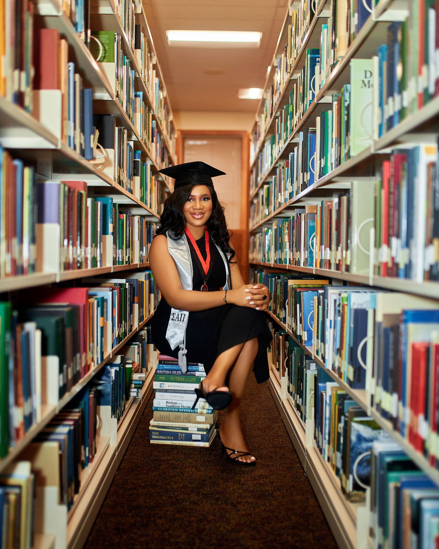Creative graduation photoshoot in library showing poses between bookshelves.
