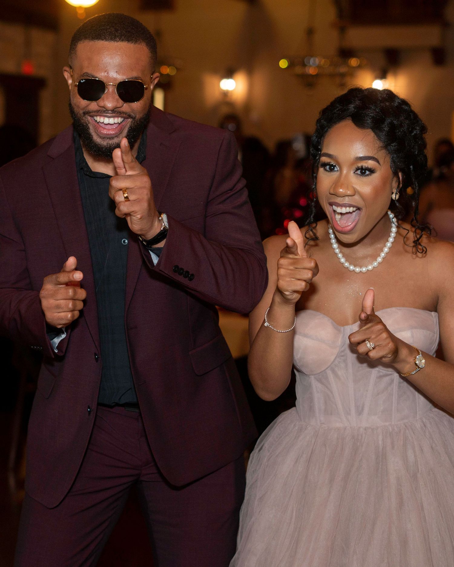 Wedding couple dances and celebrates in formal burgundy attire.