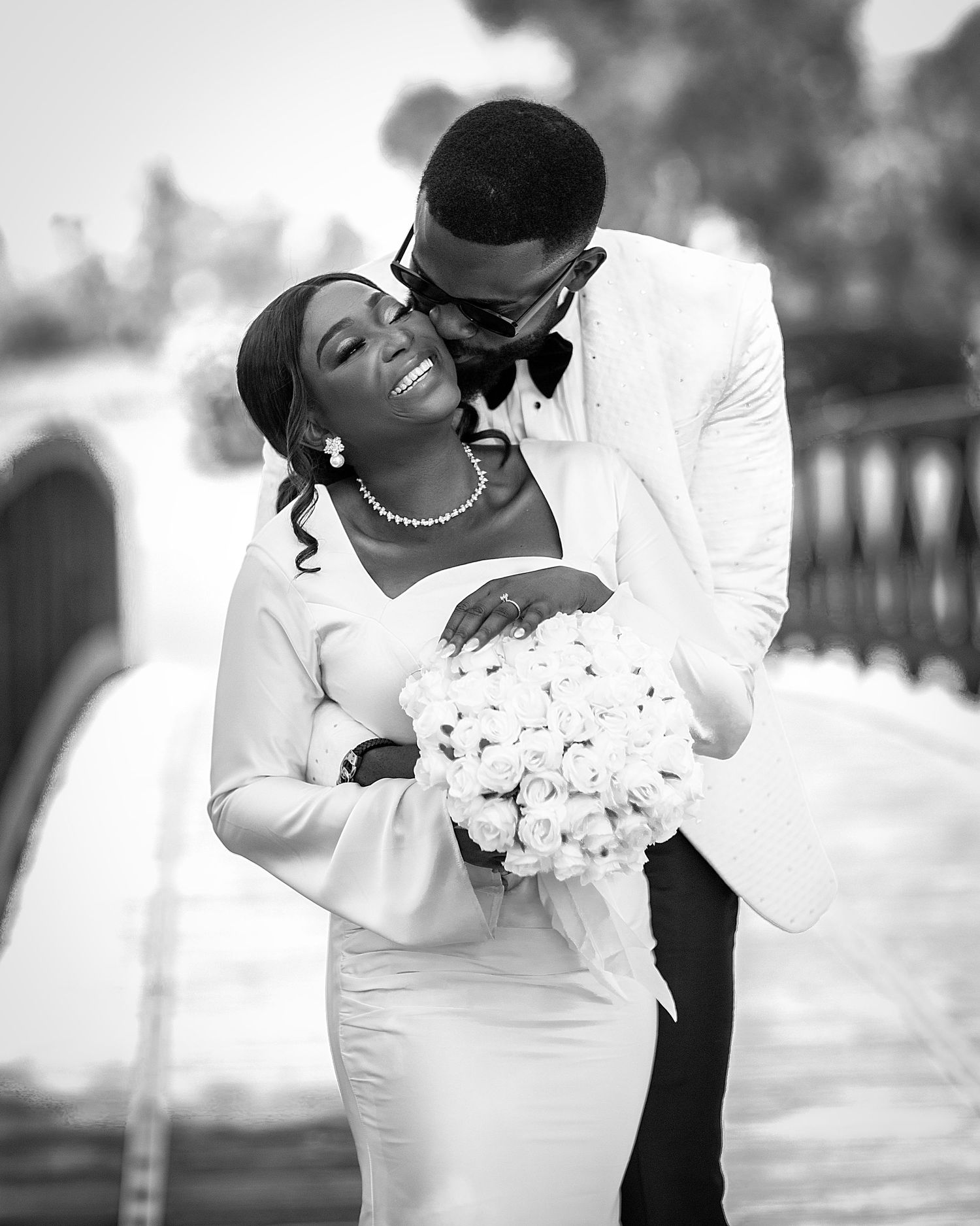 Black and white wedding photo series showing romantic moments between a couple in elegant white attire.