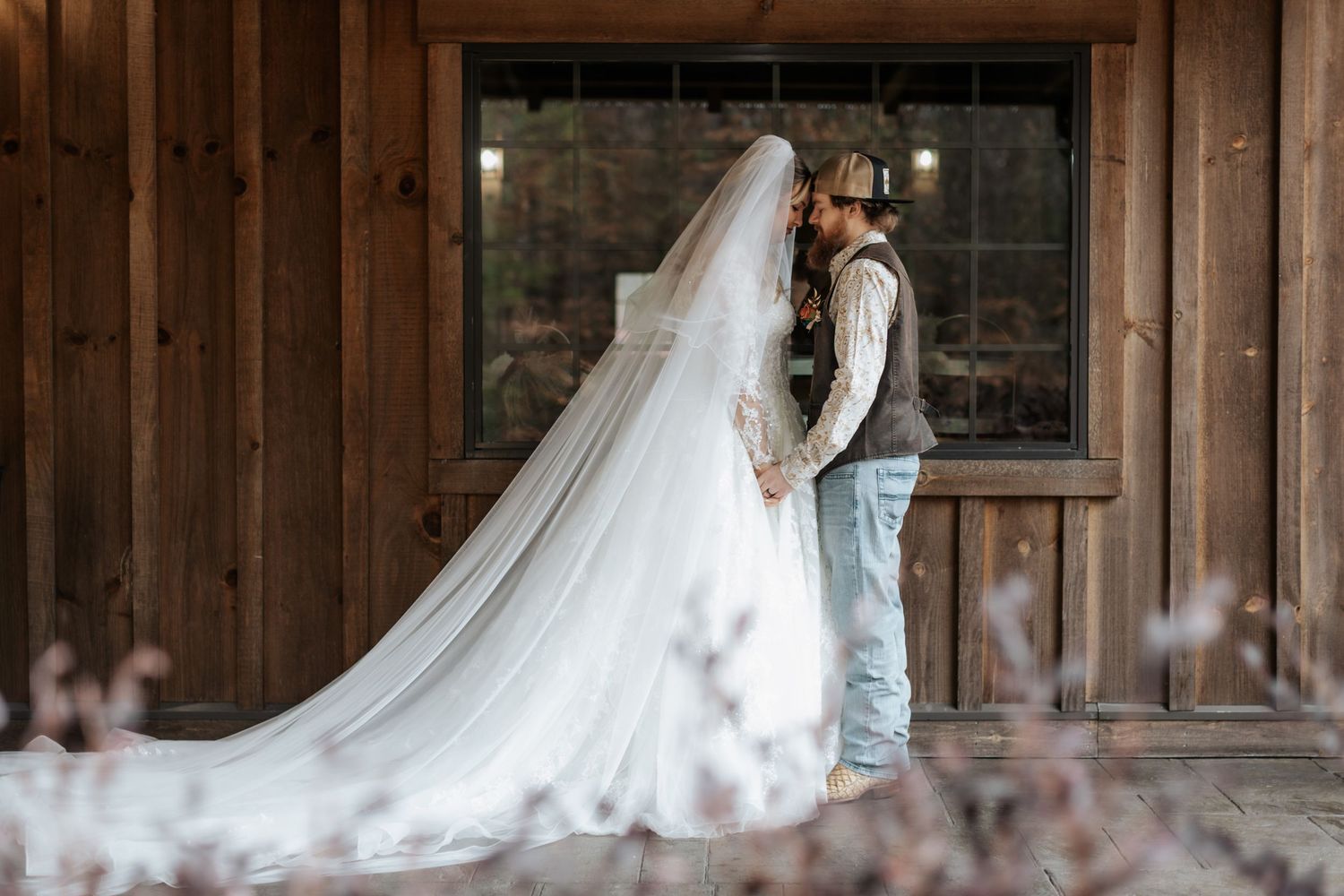 Long wedding dress train flowing across rustic wooden barn floor.