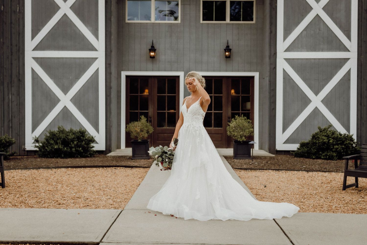 Panoramic view of a modern barn wedding venue with white trim and elegant landscaping.